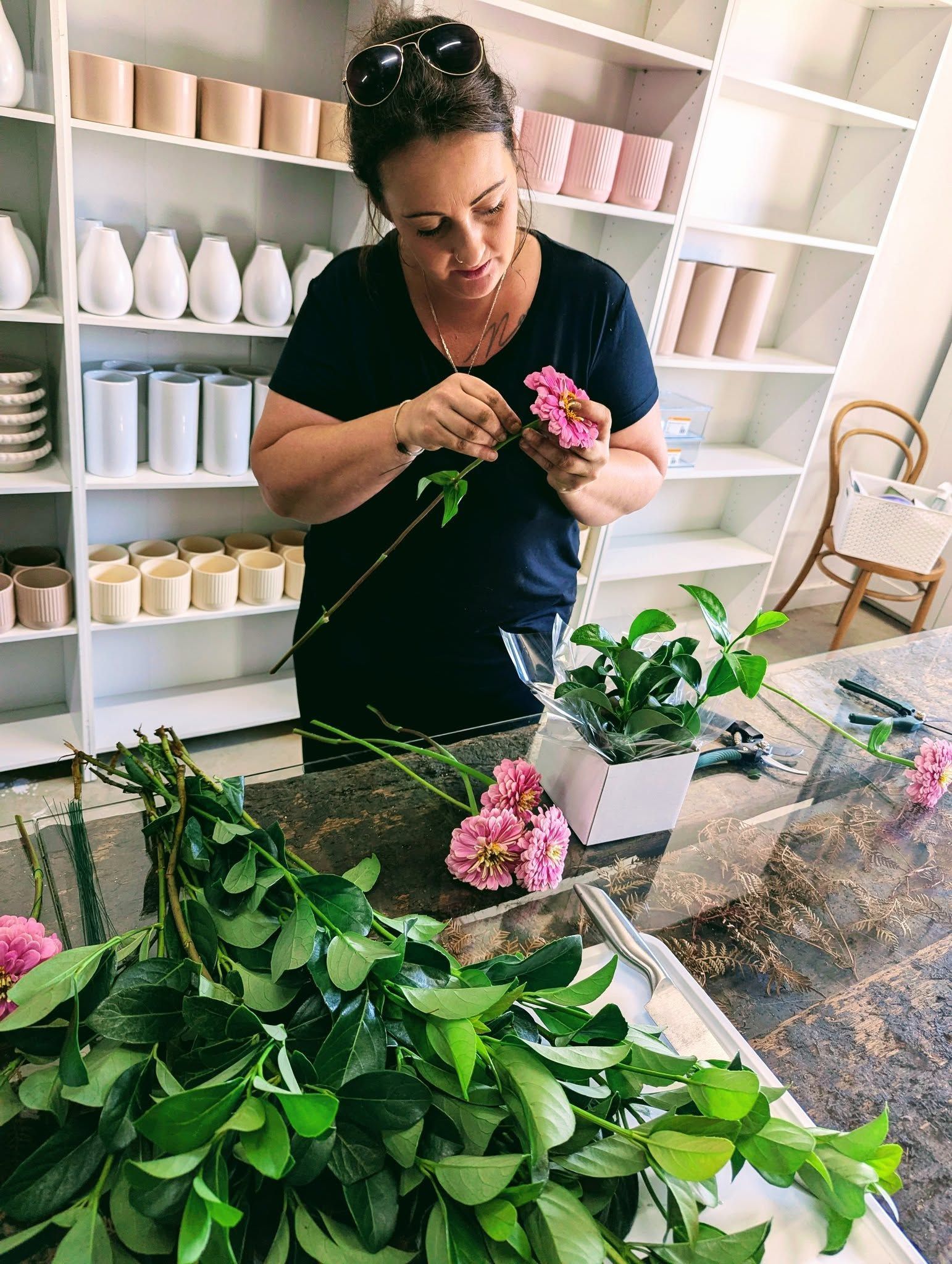 A Woman is Arranging Flowers on a Table in a Room — Hello Poppy Lane Florist In Albury, VIC