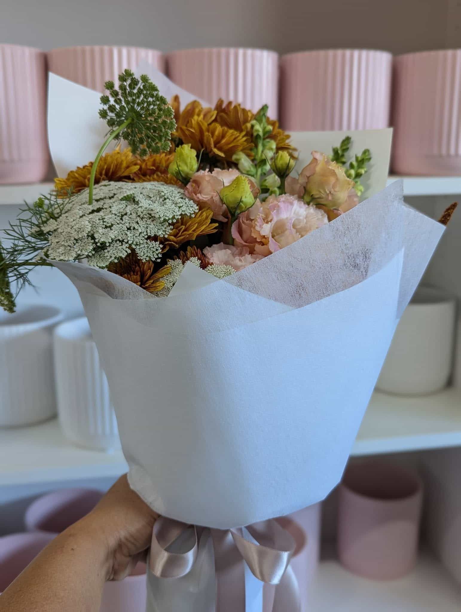 A Person is Holding a Bouquet of Flowers Wrapped in White Paper — Hello Poppy Lane Florist In Rutherglen, NSW