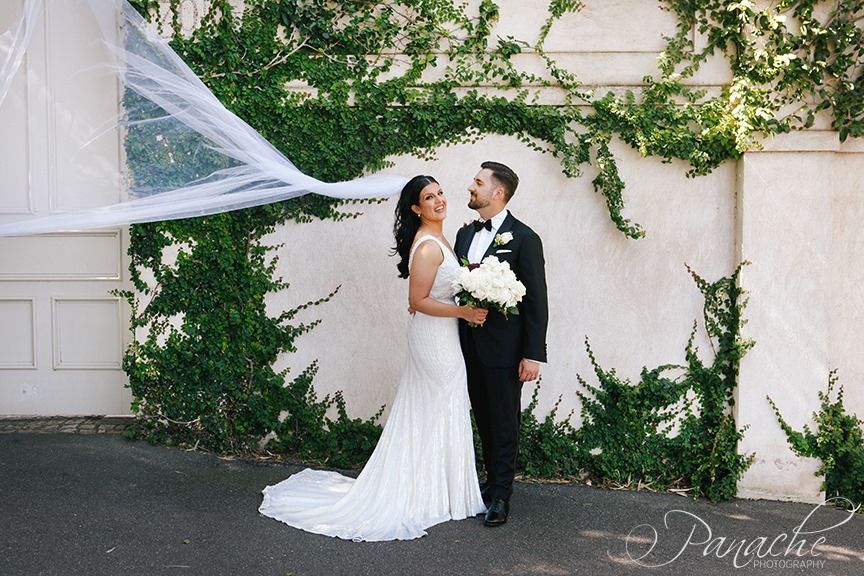 A Bride and Groom Are Posing for a Picture With Their Veil Blowing in the Wind — Hello Poppy Lane Florist in Rutherglen, NSW