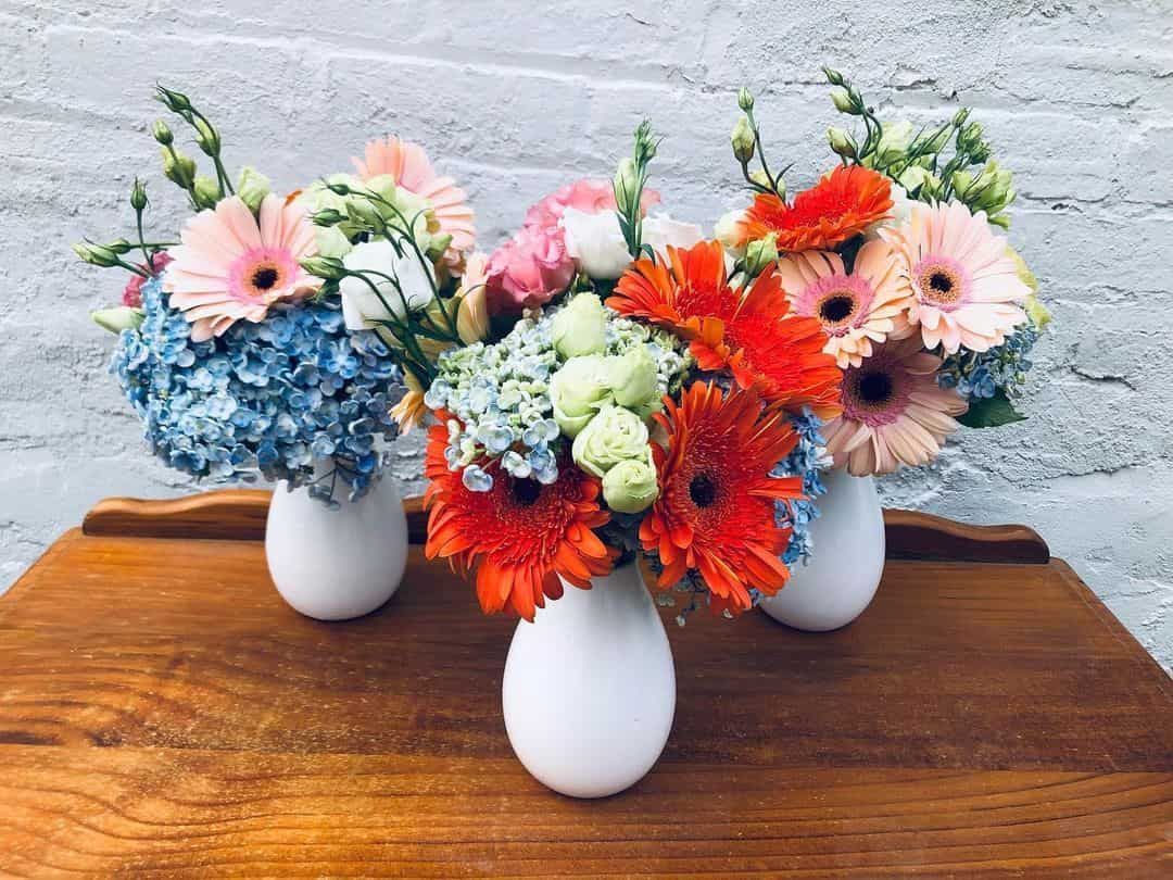 Three Vases Filled with Flowers Are Sitting on A Wooden Table — Hello Poppy Lane Florist In Ebden, VIC