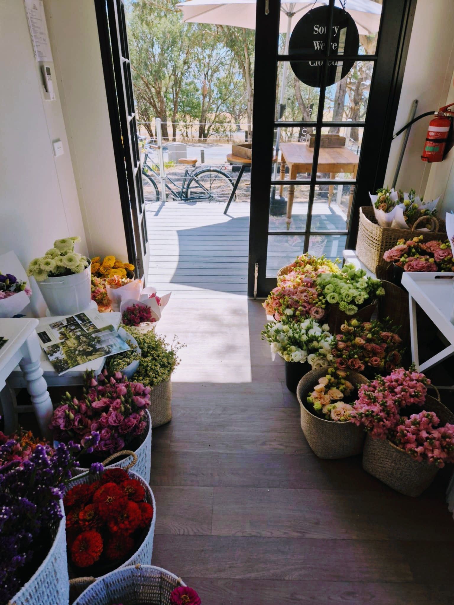 A flower shop with various colourful bouquets in baskets near a doorway to an outdoor patio — Hello Poppy Lane Florist In Albury, NSW