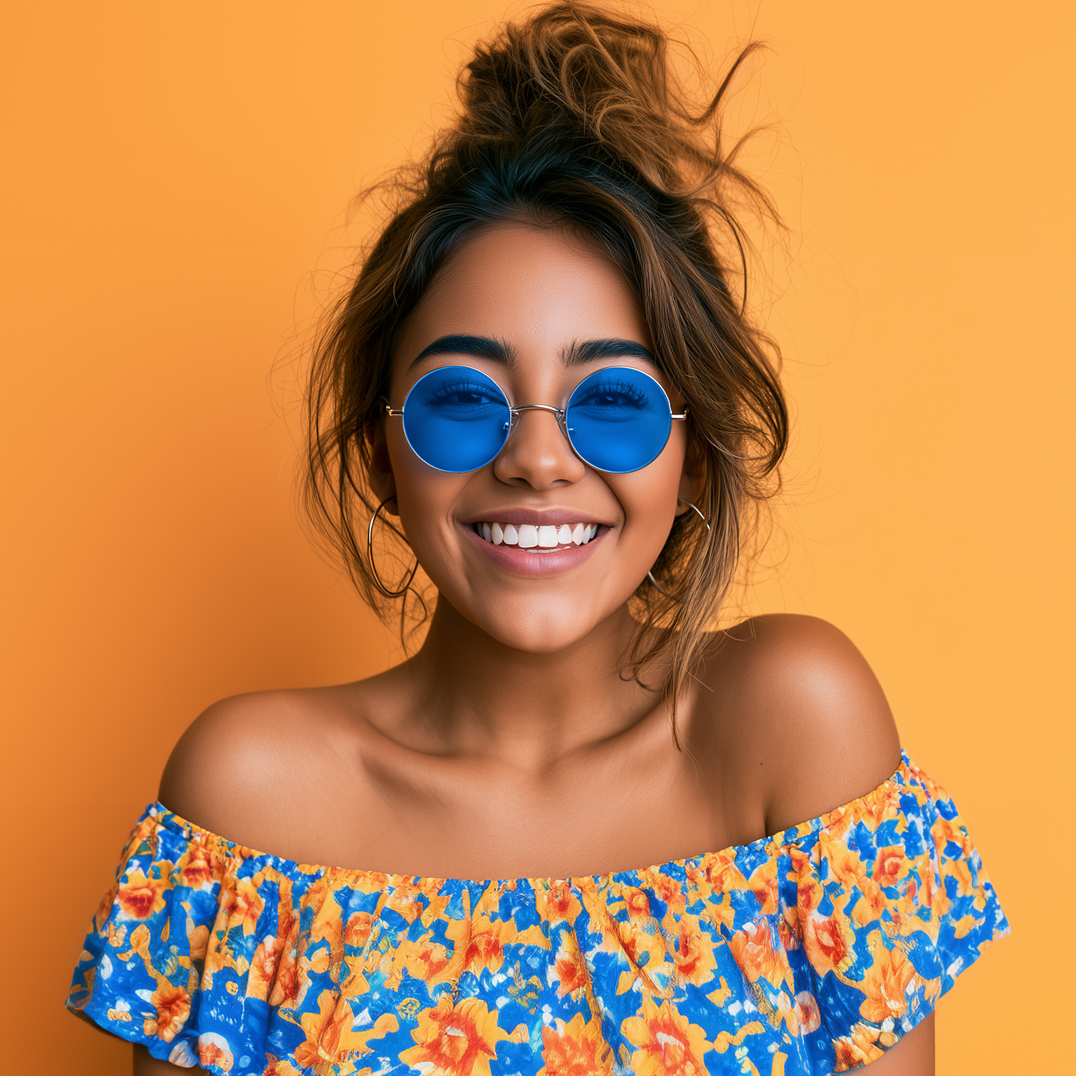 Smiling woman in blue sunglasses and a blue-orange floral off-shoulder top against an orange background