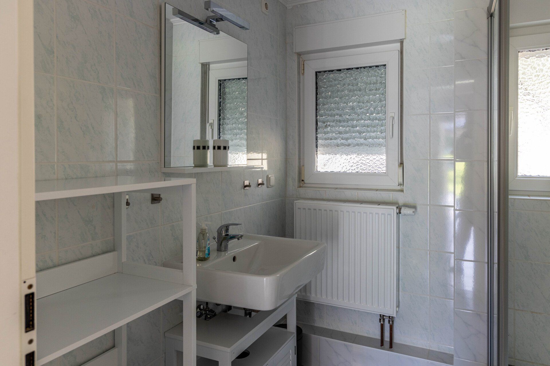 Ein Badezimmer mit Waschbecken, Spiegel und Fenster.