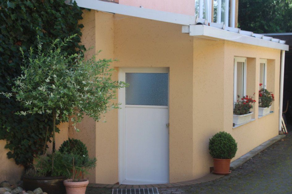 Ein Haus mit einer weißen Tür und Topfpflanzen davor