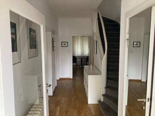 Ein Flur mit einer schwarzen Treppe, die in den zweiten Stock führt