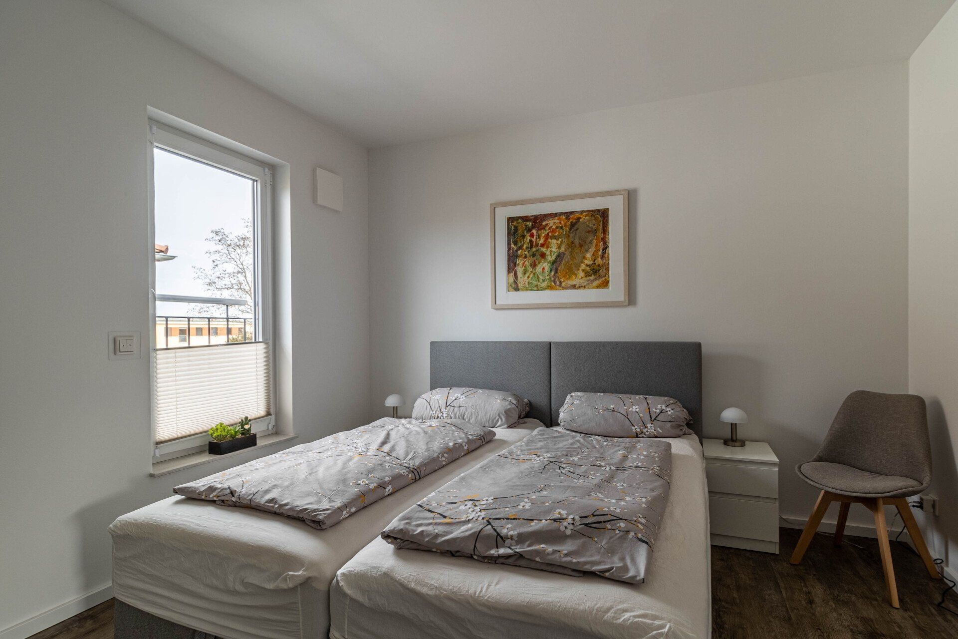 Ein Schlafzimmer mit zwei Betten, einem Stuhl und einem Fenster.