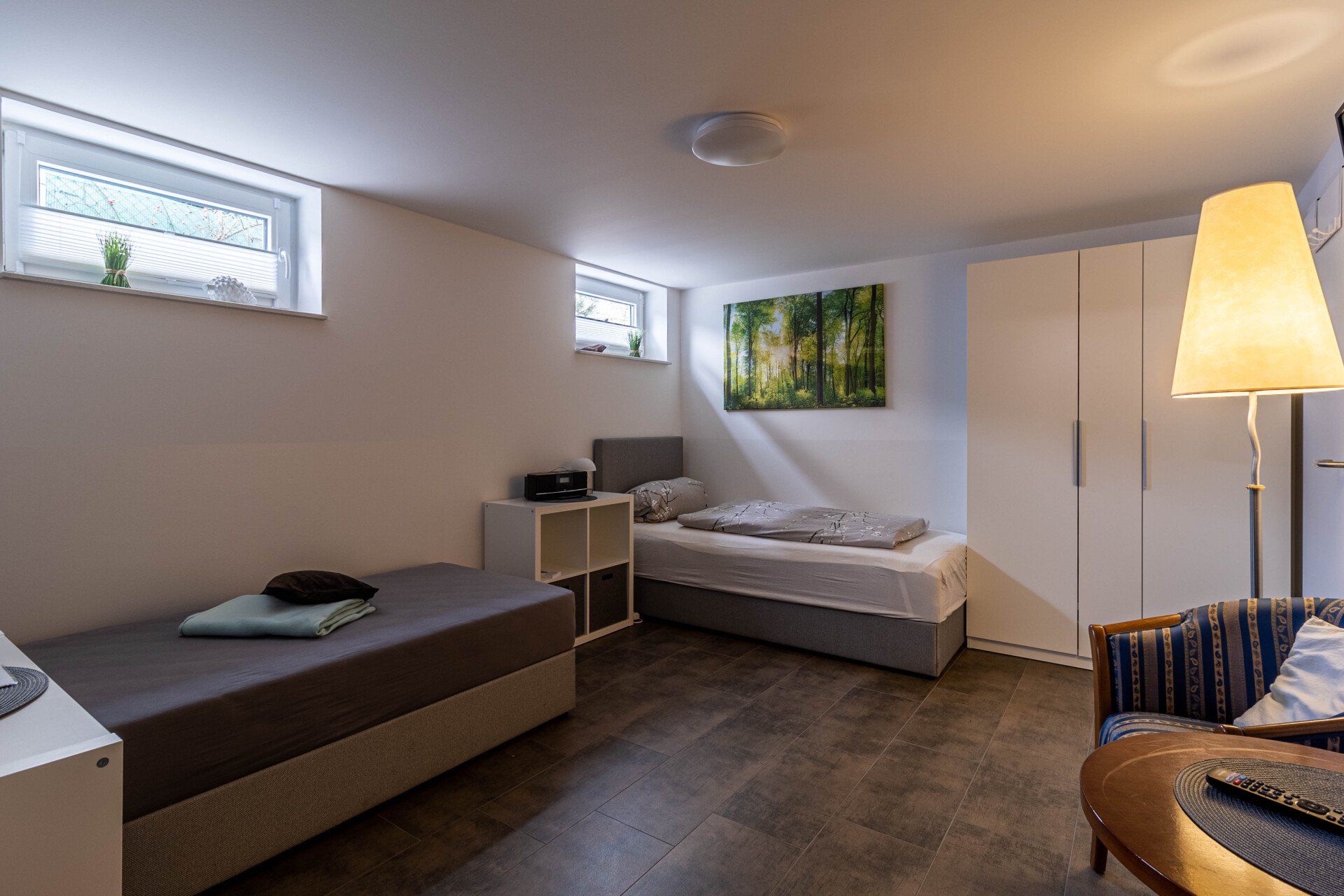 Ein Schlafzimmer mit zwei Betten, einer Couch, einer Lampe und einem Gemälde an der Wand.