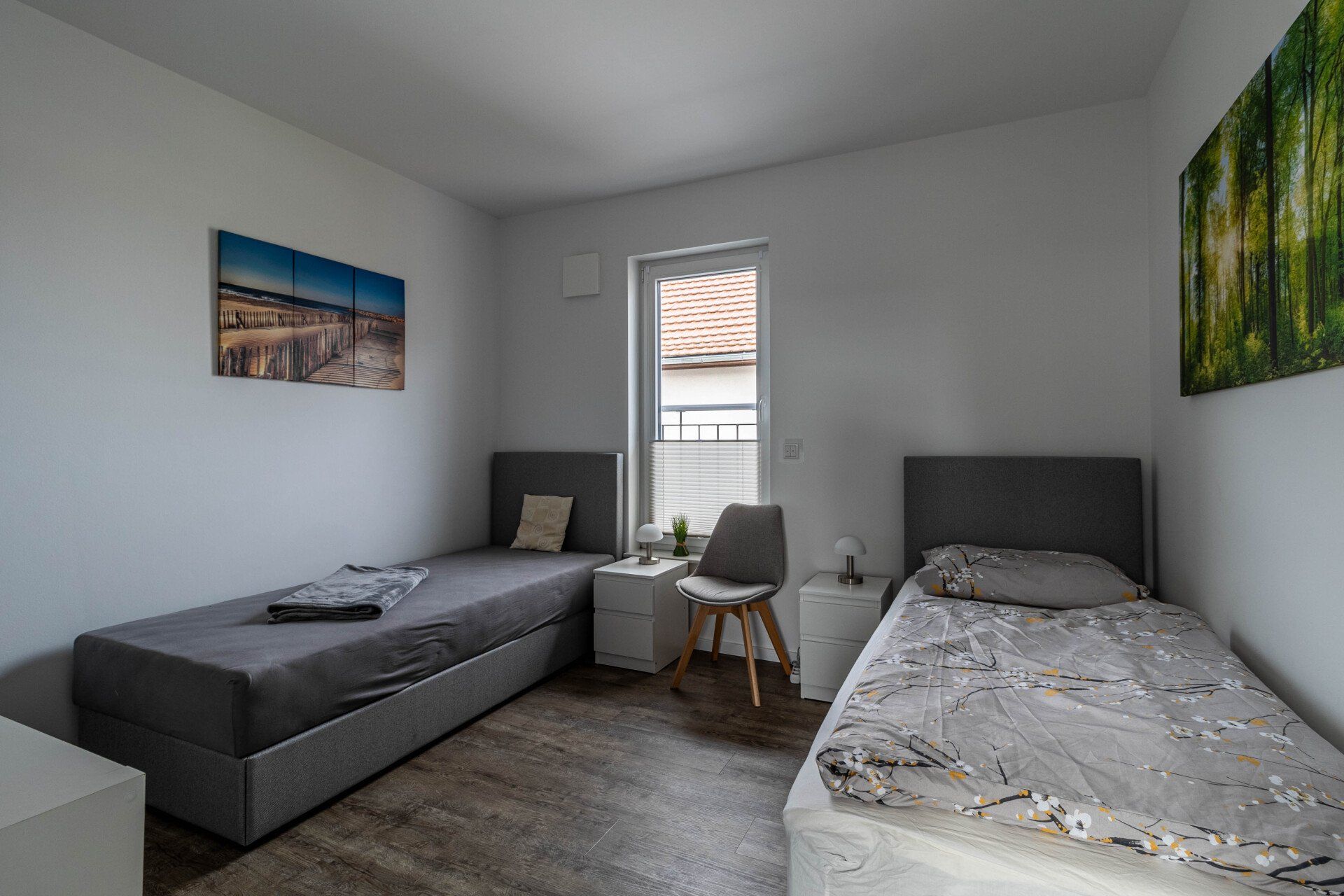 Ein Schlafzimmer mit zwei Betten, einem Stuhl und einem Fenster.