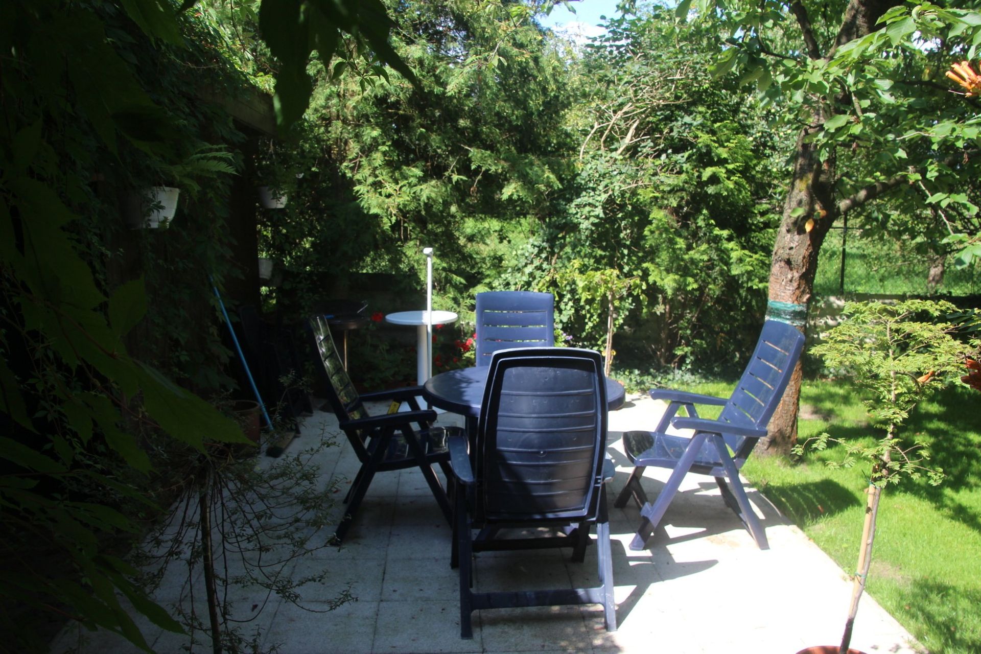 Ein Tisch und Stühle auf einer Terrasse mit Bäumen im Hintergrund