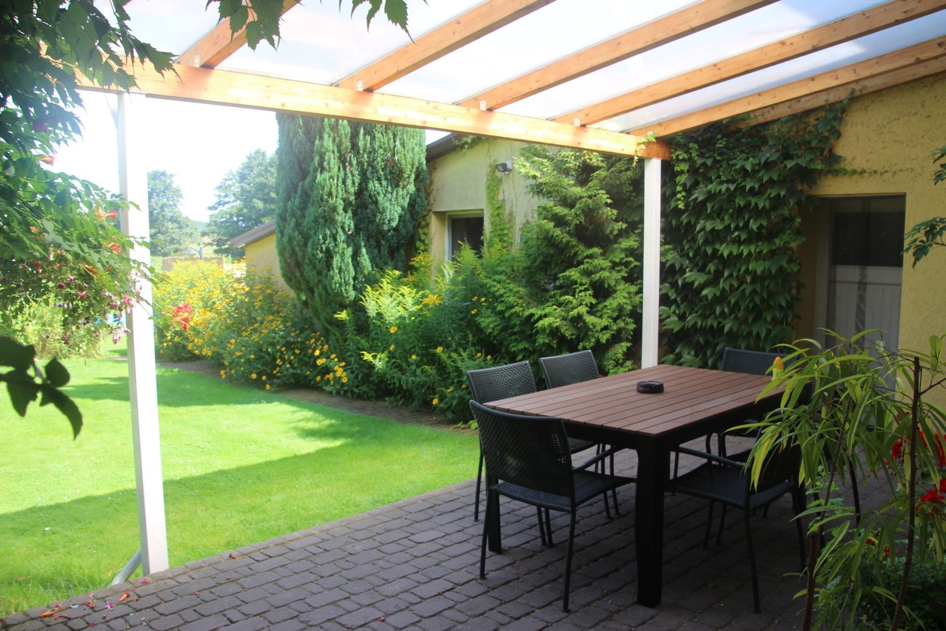 Eine Terrasse mit Tisch und Stühlen unter einem Baldachin