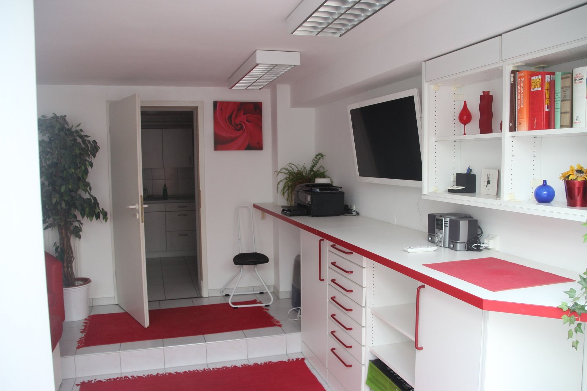 Ein Raum mit weißen Schränken und roten Arbeitsplatten