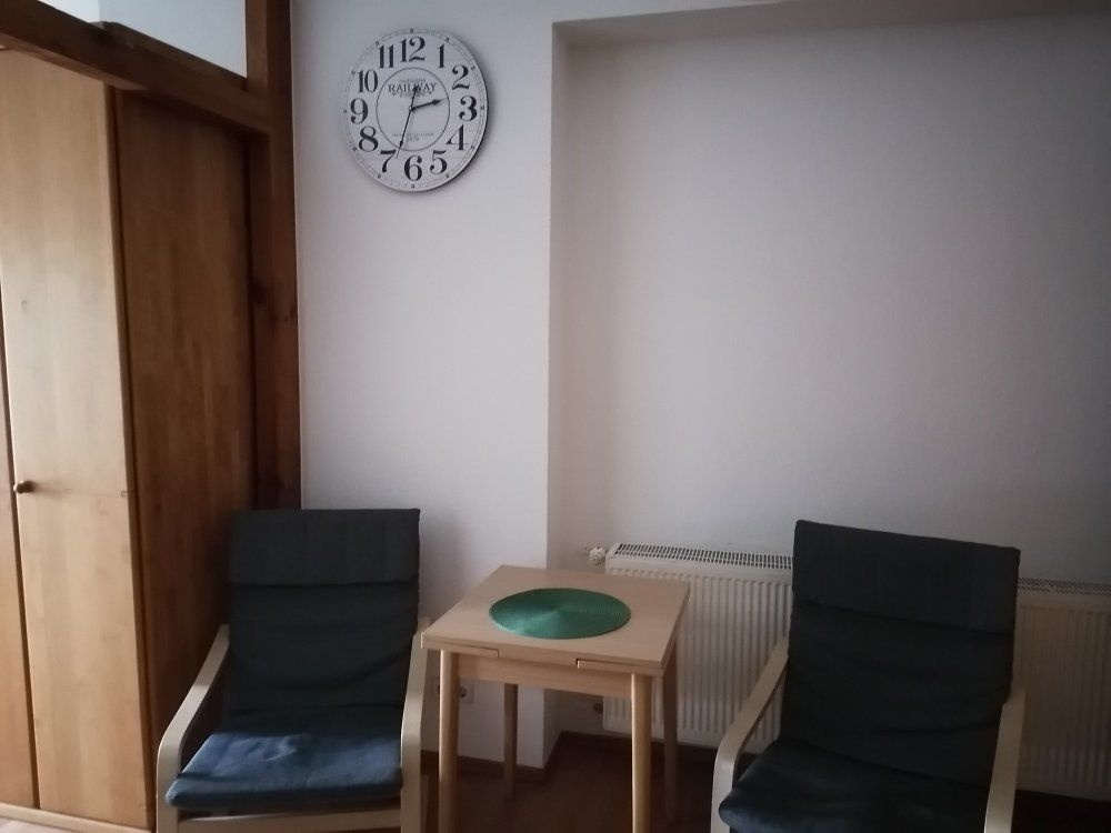 Zwei Stühle und ein Tisch in einem Raum mit einer Uhr an der Wand