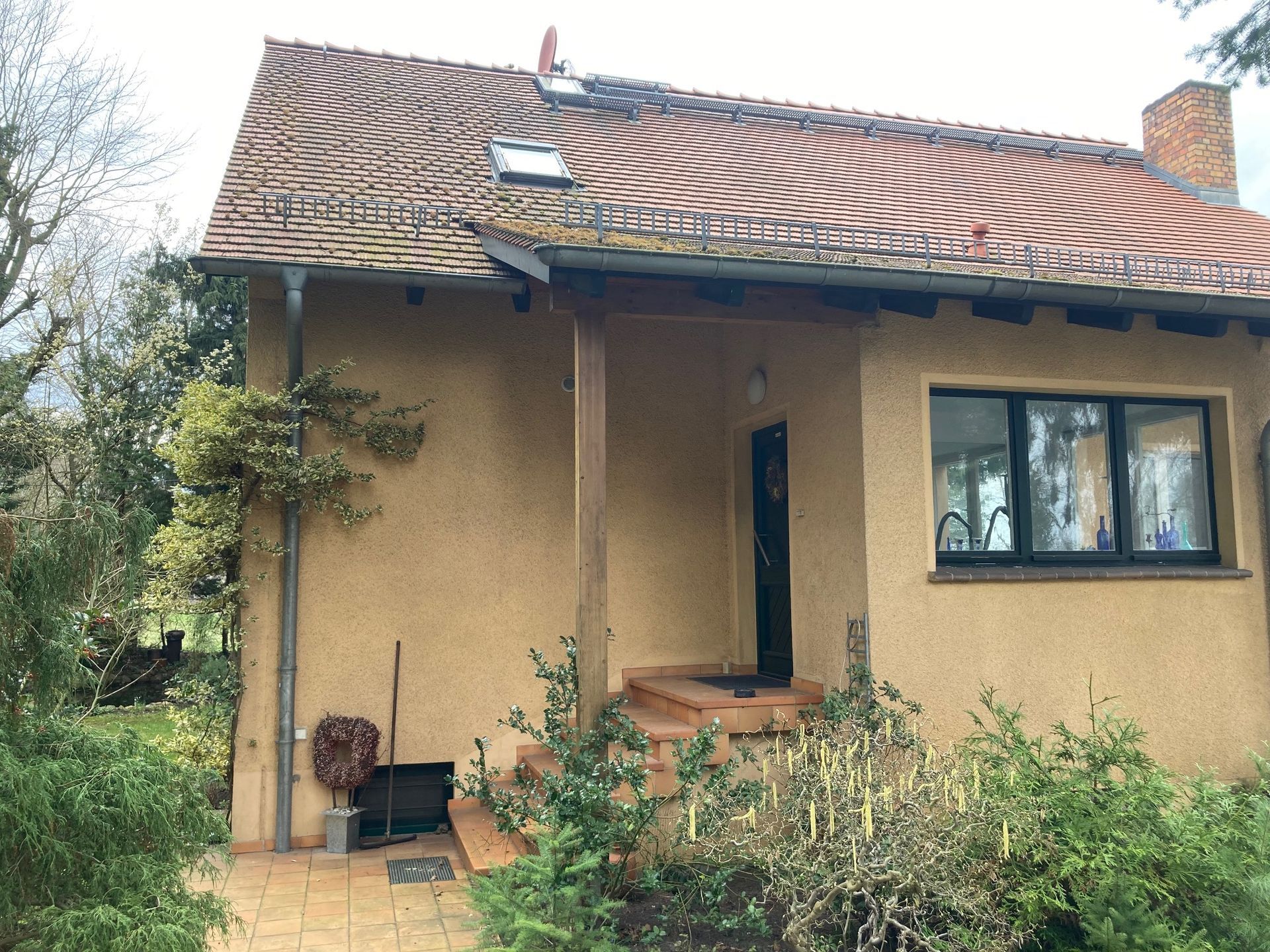 Ein kleines Haus mit einem roten Ziegeldach und einer Veranda