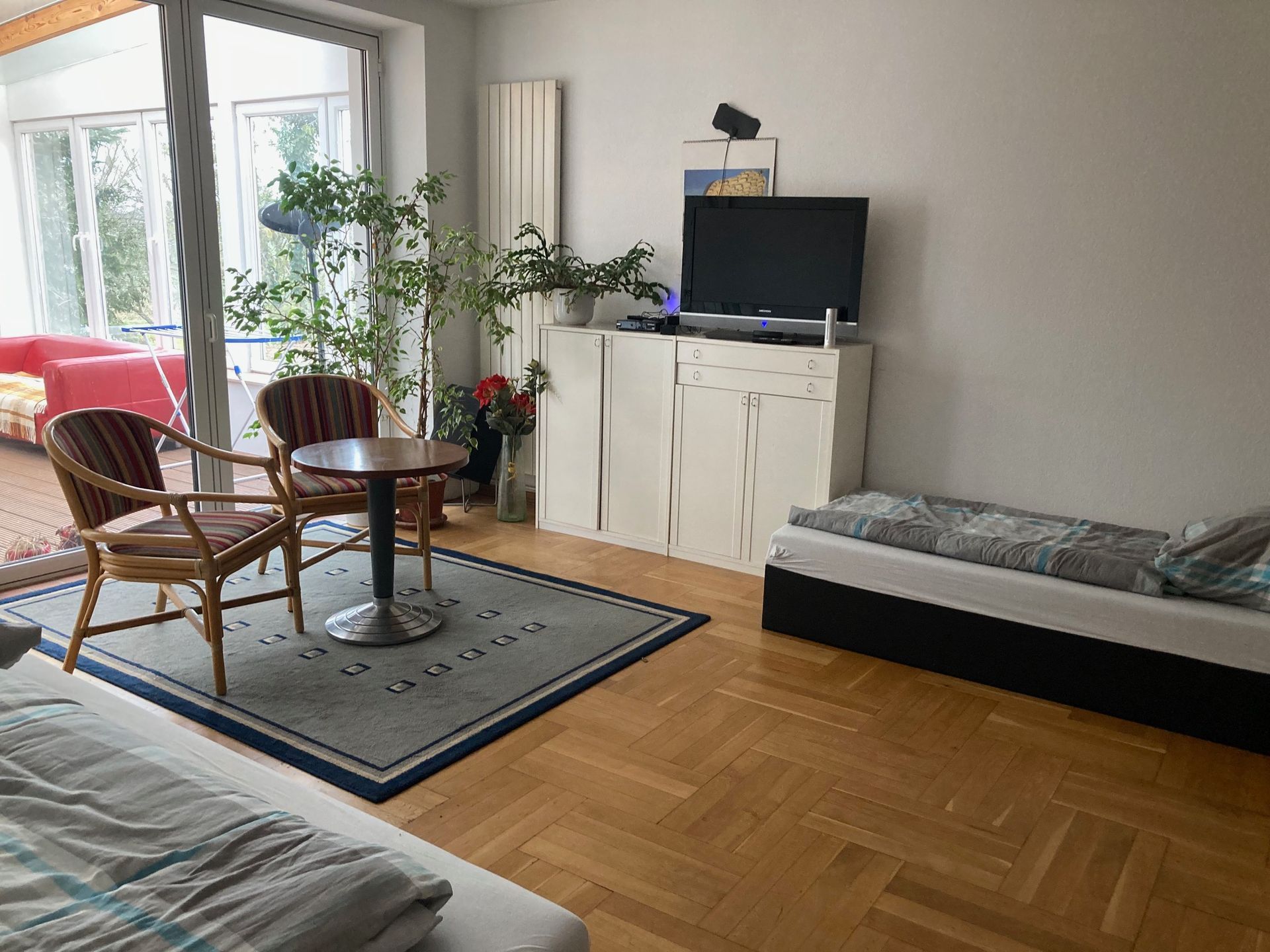 Ein Wohnzimmer mit zwei Betten, einem Tisch, Stühlen und einem Fernseher.