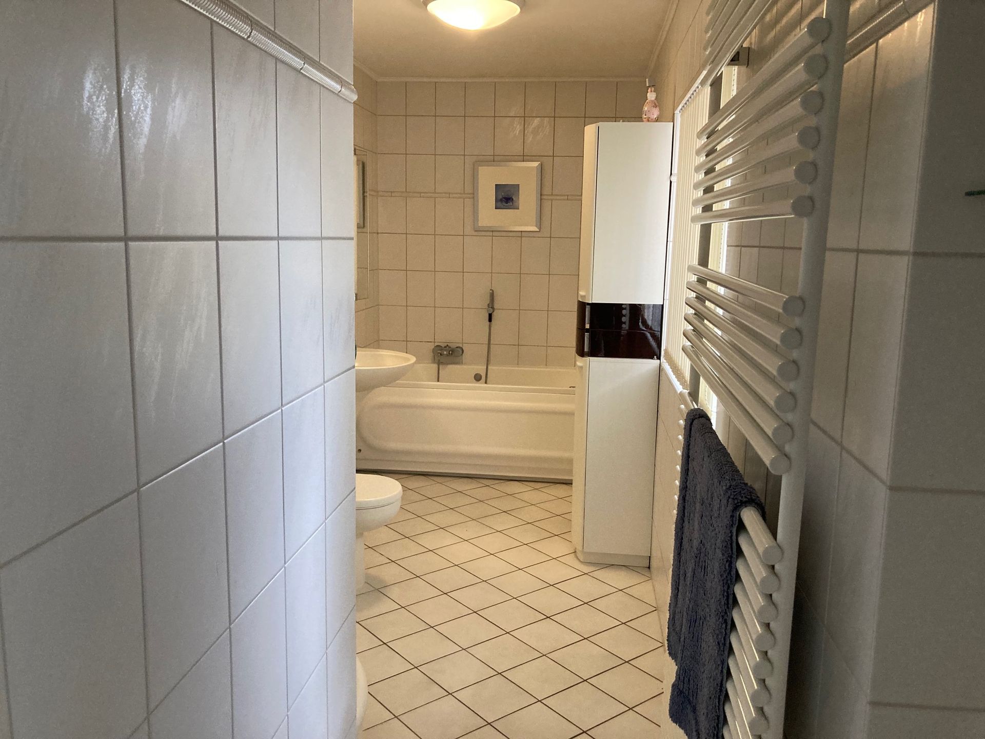 Ein Badezimmer mit weißen Fliesen und einer Badewanne