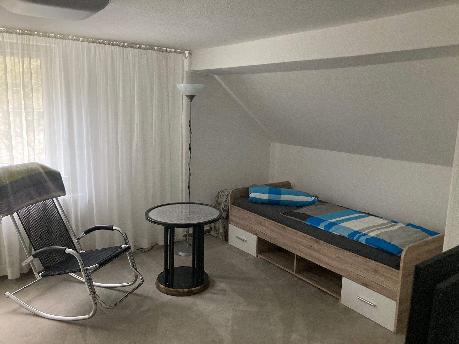 Ein Schlafzimmer mit Schaukelstuhl, Tisch und Bett