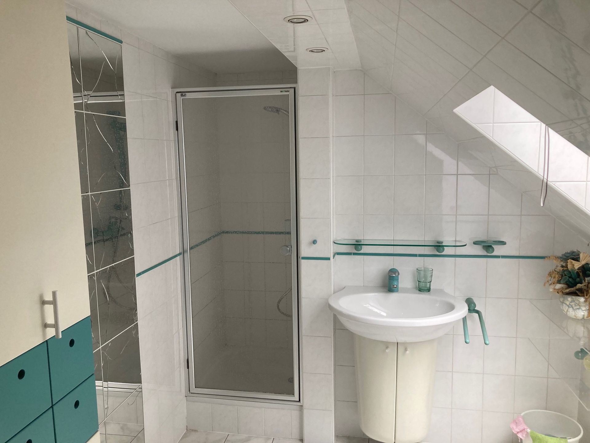 Ein Badezimmer mit Waschbecken, Dusche und Oberlicht