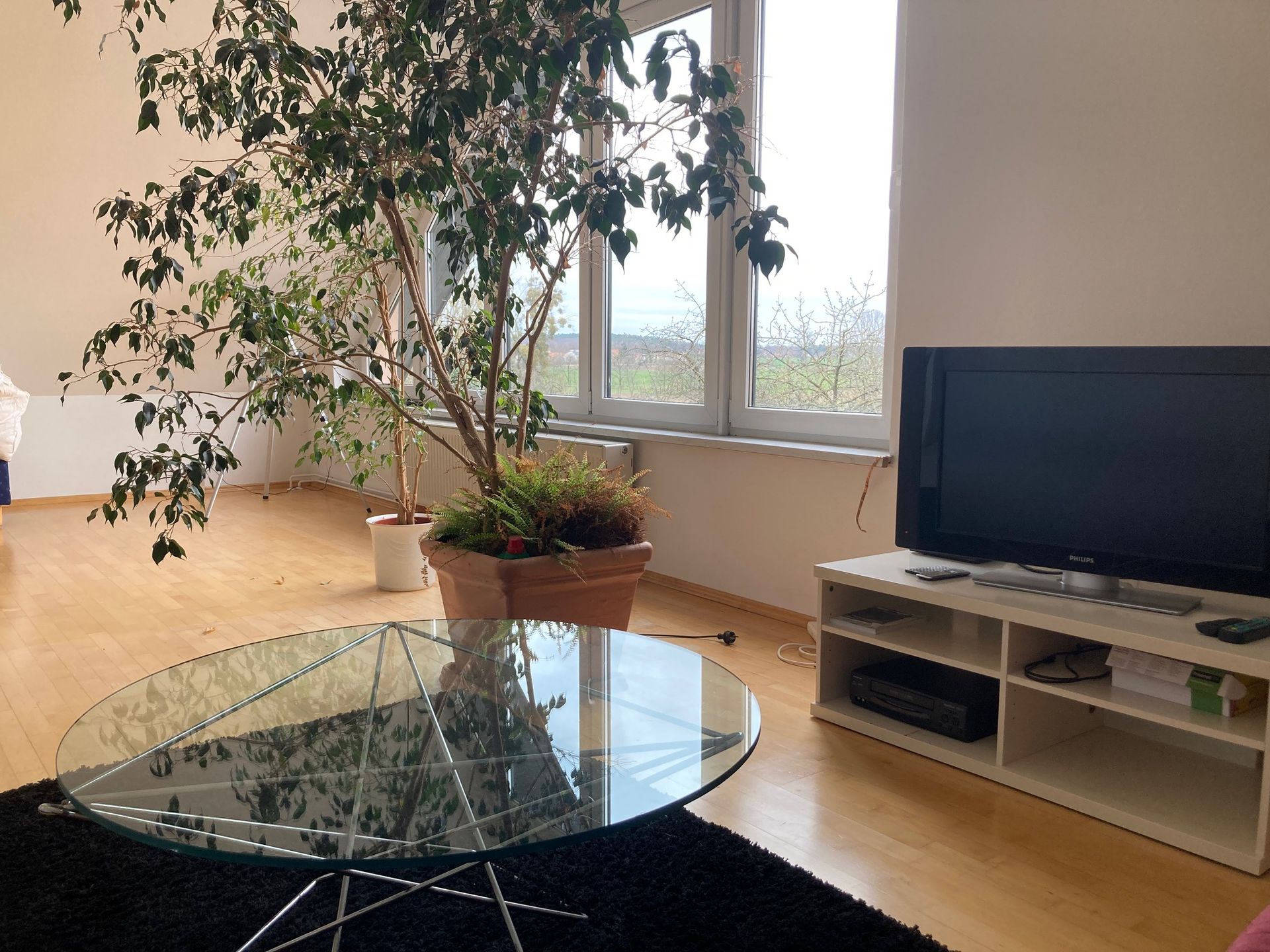 Ein Wohnzimmer mit einem Couchtisch aus Glas und einem Fernseher