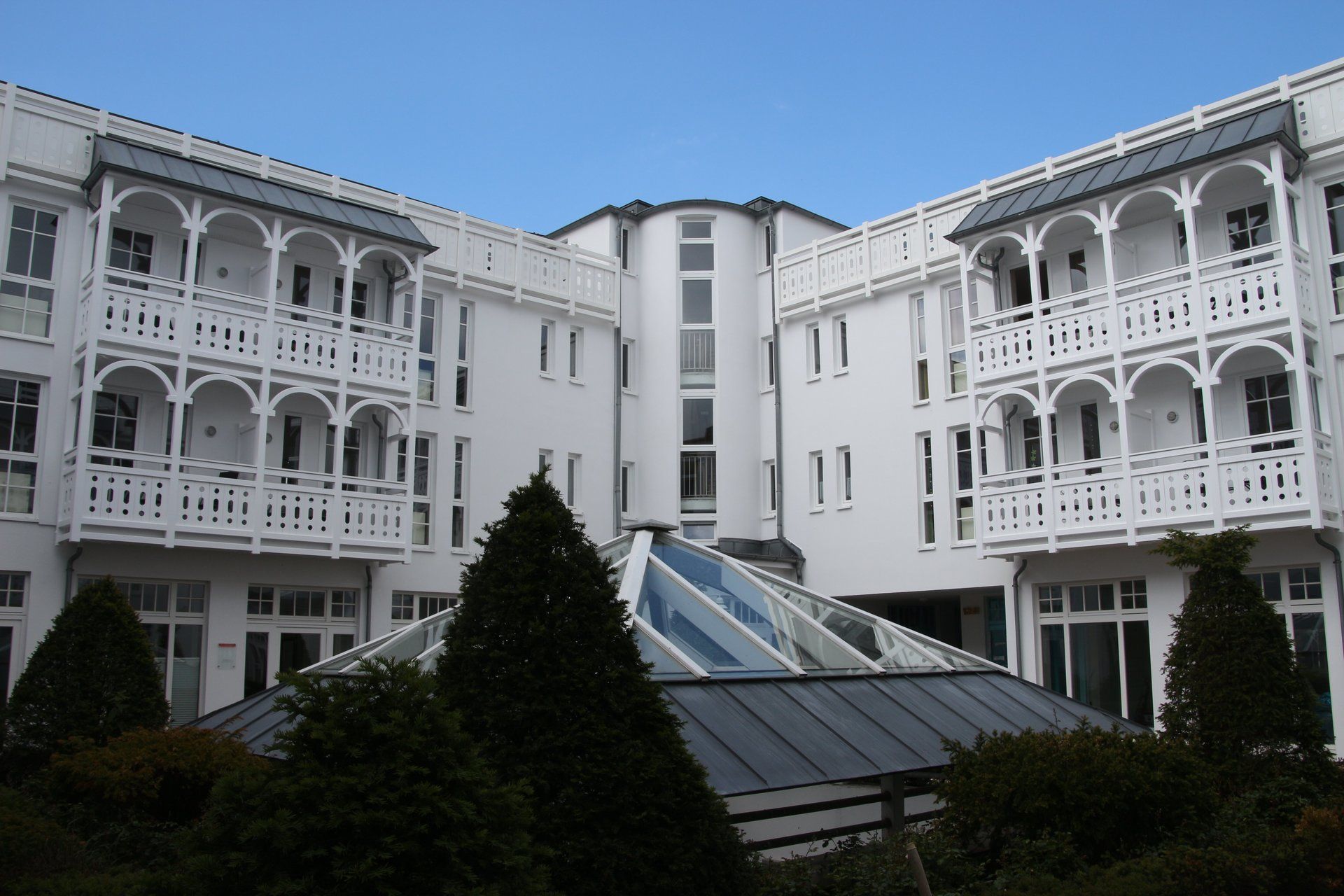 Ein großes weißes Gebäude mit Balkonen und Bäumen davor