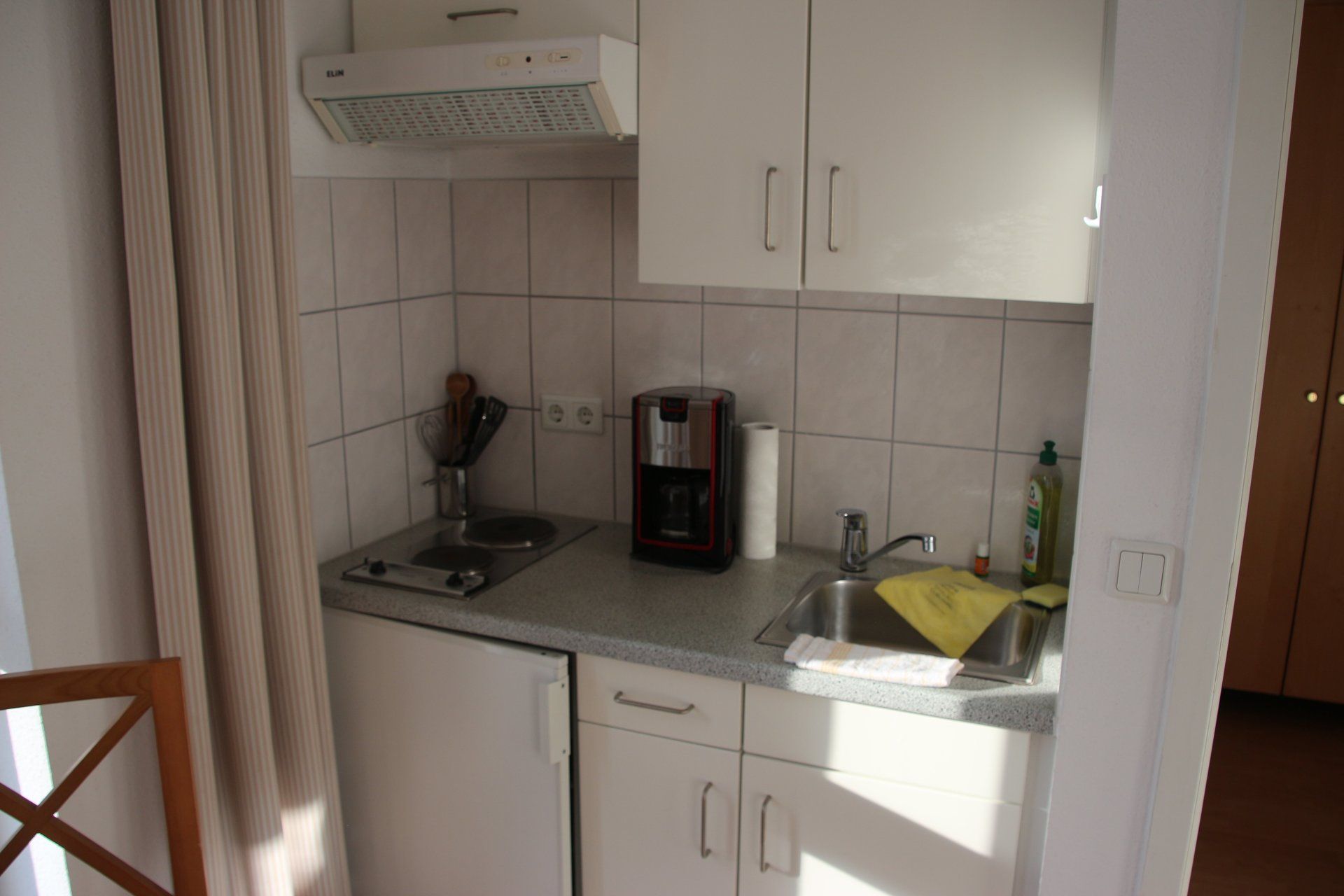 Eine kleine Küche mit weißen Schränken und einer Spüle