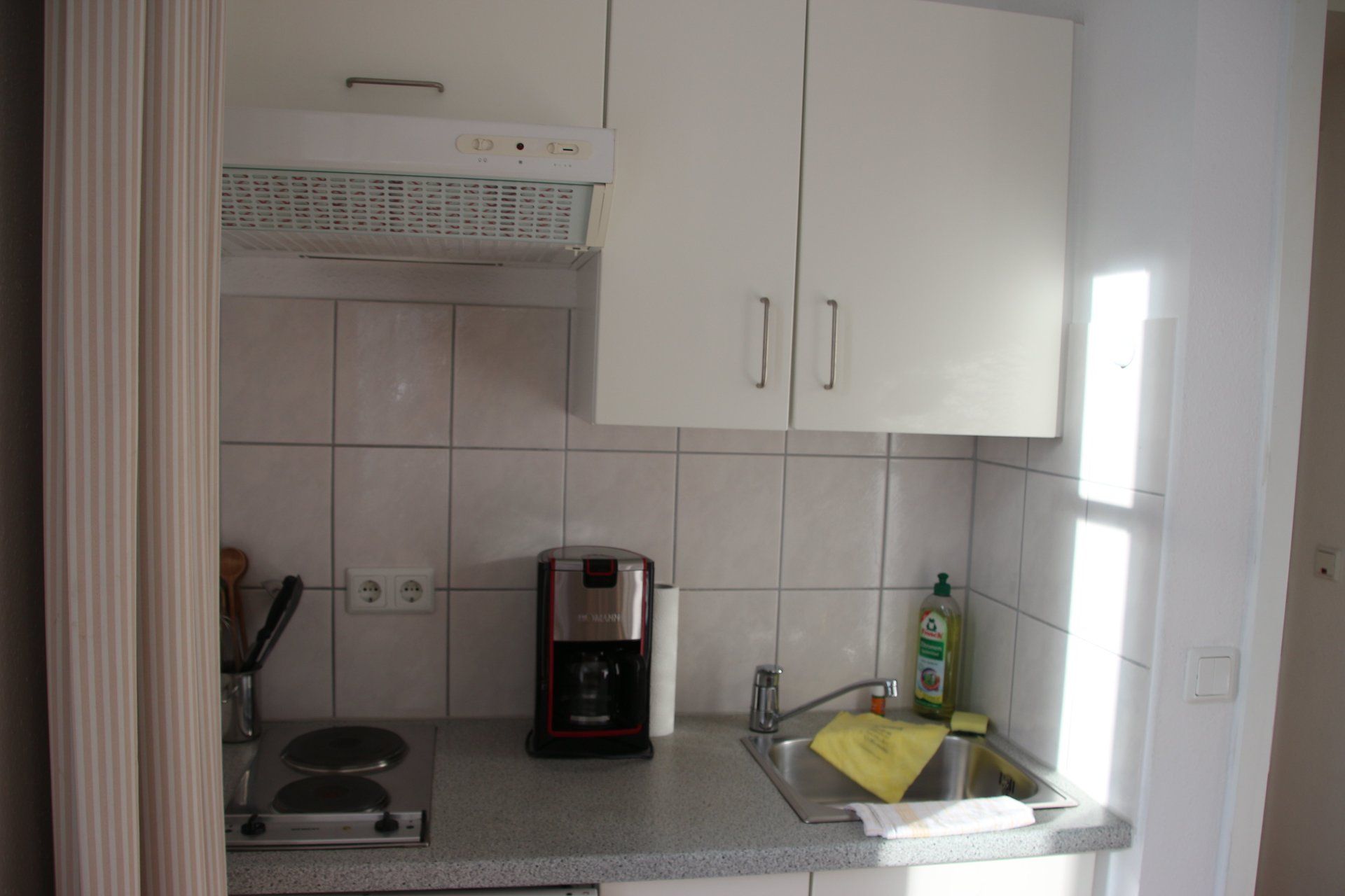 Eine kleine Küche mit weißen Schränken und einer Spüle