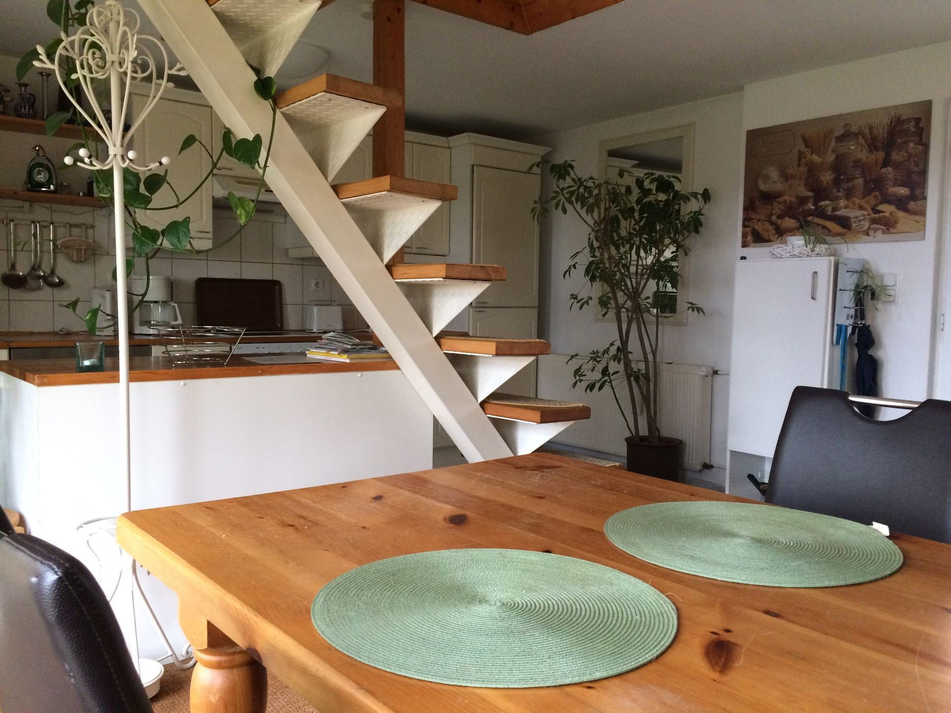 Ein Holztisch mit grünen Tischsets und einer Treppe im Hintergrund