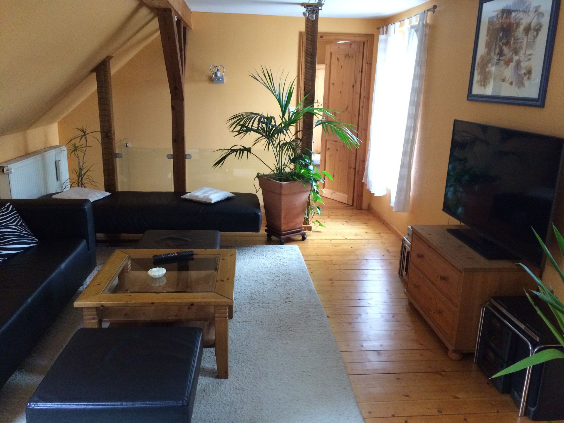 Ein Wohnzimmer mit einer schwarzen Couch und einem Flachbildfernseher