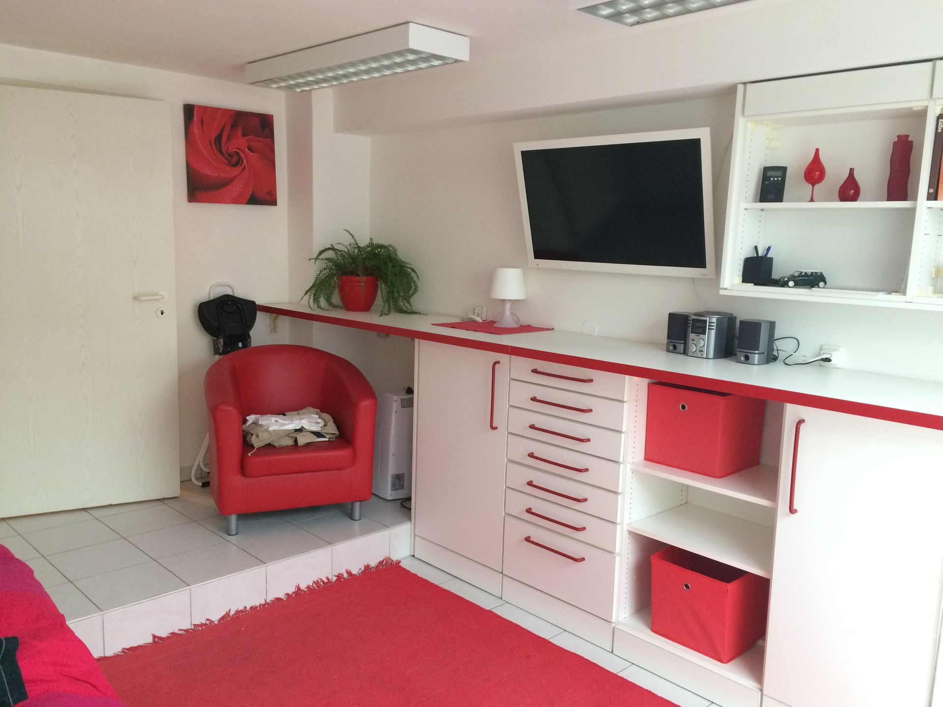 Ein Wohnzimmer mit einem roten Stuhl und einem Flachbildfernseher