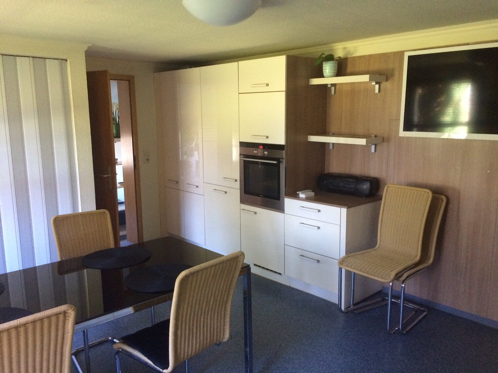 Eine Küche mit Tisch und Stühlen und einem Flachbildfernseher