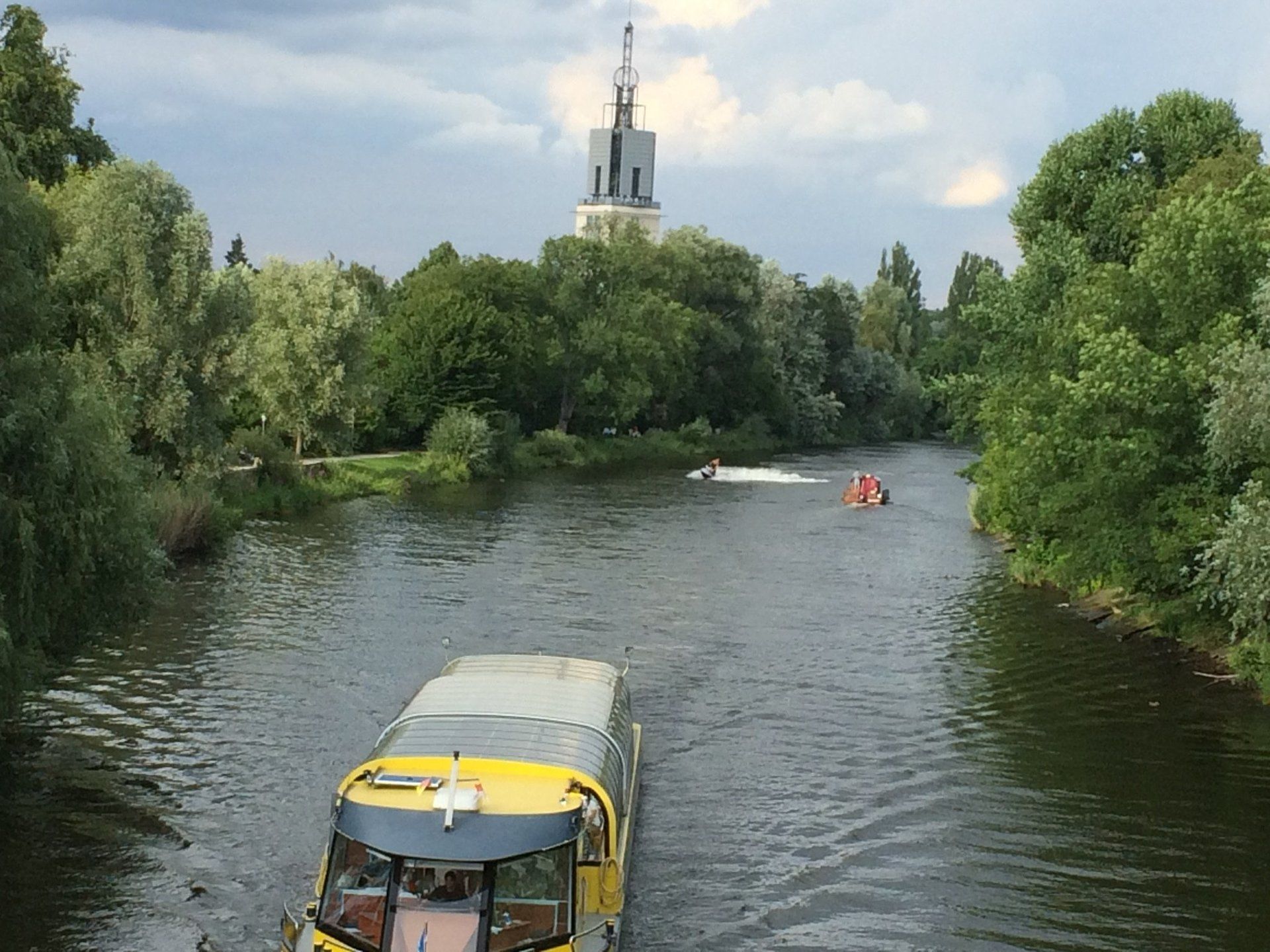 Ein Boot fährt einen Fluss hinunter, im Hintergrund ist ein Turm