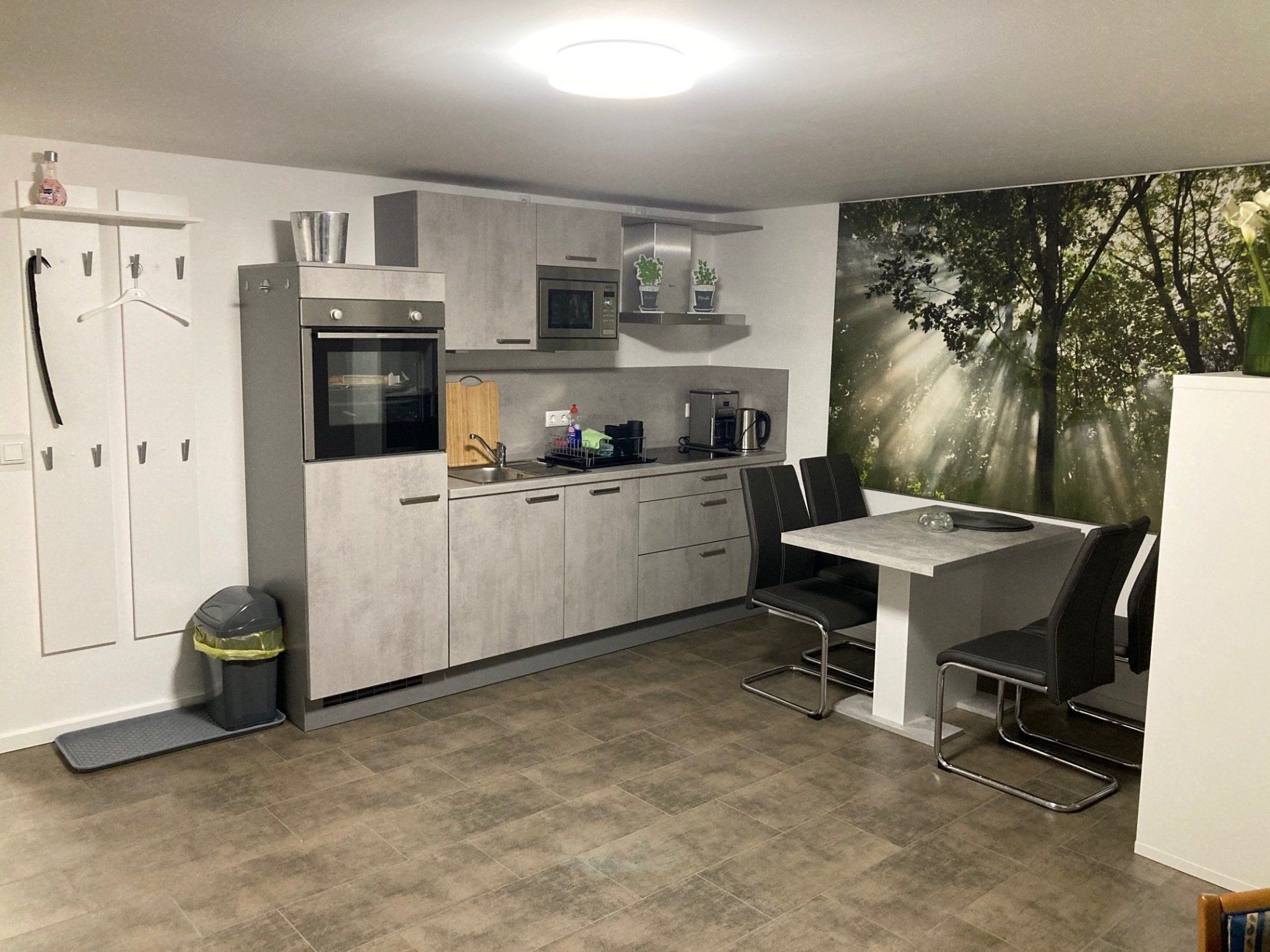 Eine Küche mit Tisch und Stühlen und einem Bild von Bäumen an der Wand.