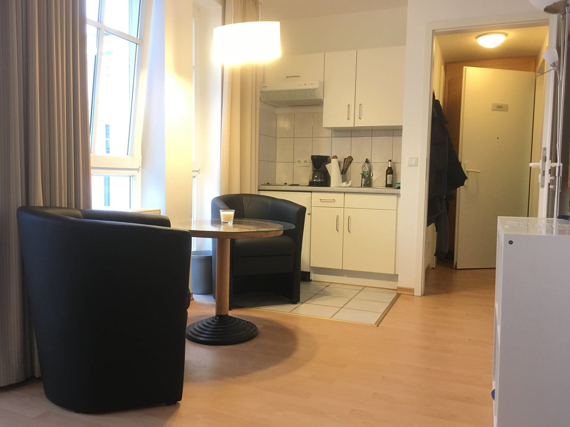 Ein Wohnzimmer mit Tisch und Stühlen und einer Küche im Hintergrund.