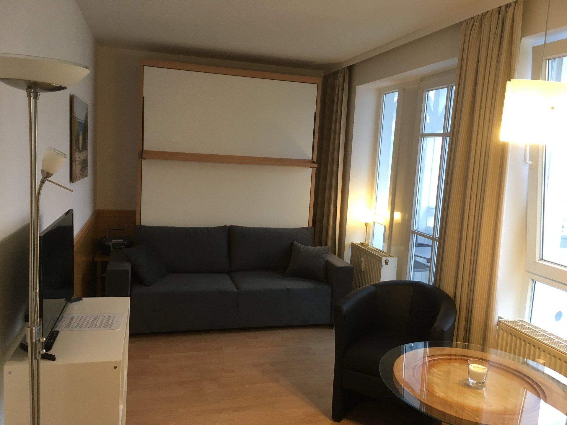 Ein Wohnzimmer mit Couch, Sessel, Tisch und Fernseher
