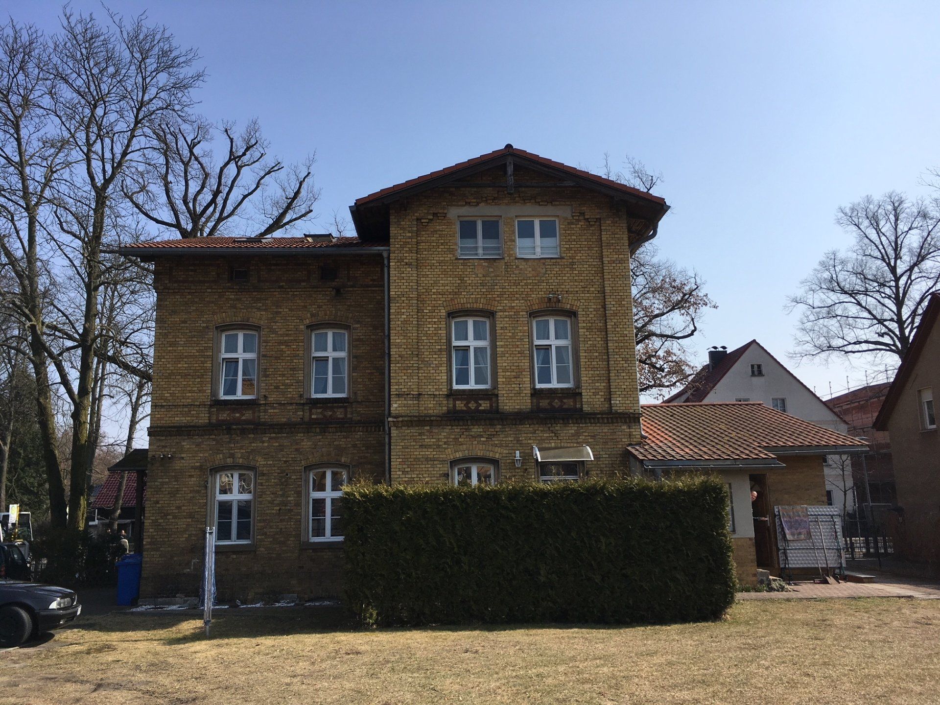 Ein großes Backsteingebäude mit einer Hecke davor