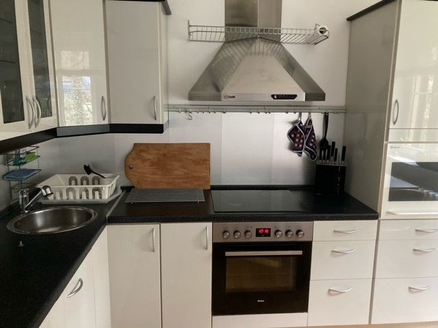 Eine Küche mit weißen Schränken und schwarzen Arbeitsplatten