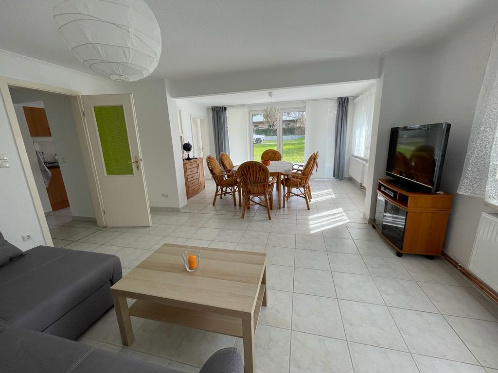 Ein Wohnzimmer mit Couch, Tisch, Stühlen und Fernseher.