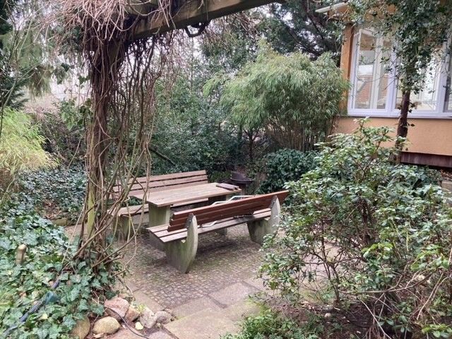 Ein Picknicktisch und eine Bank in einem Garten neben einem Haus.