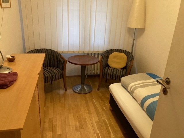 Ein Schlafzimmer mit einem Einzelbett, einem Tisch und Stühlen