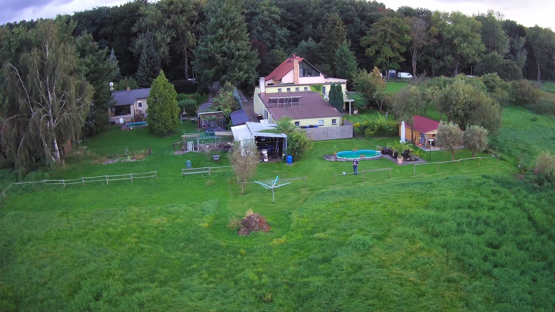 Eine Luftaufnahme eines Hauses inmitten einer üppigen grünen Wiese, umgeben von Bäumen.