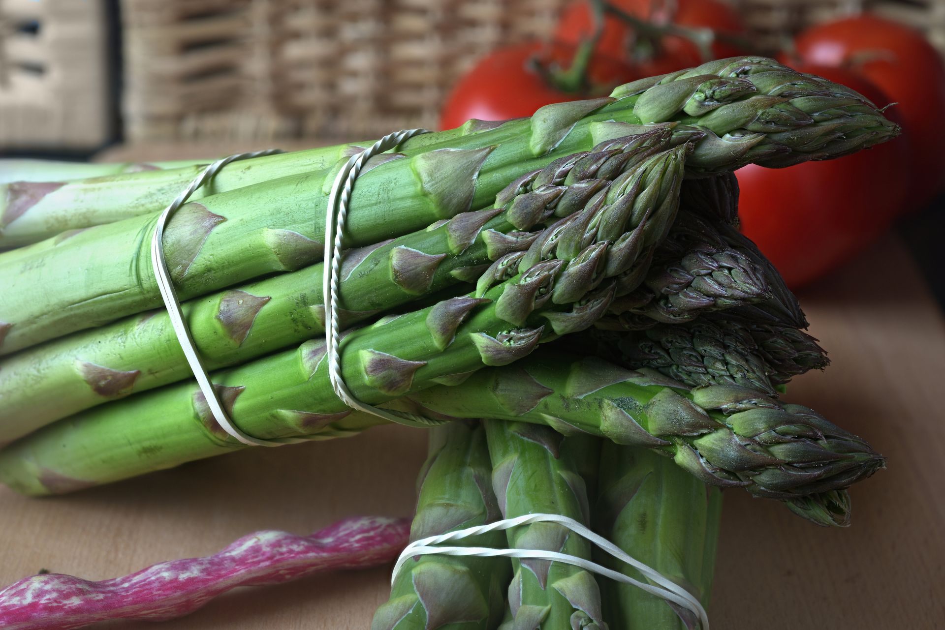 Ein Bündel grüner Spargel, mit einer Schnur zusammengebunden, auf einem Tisch.