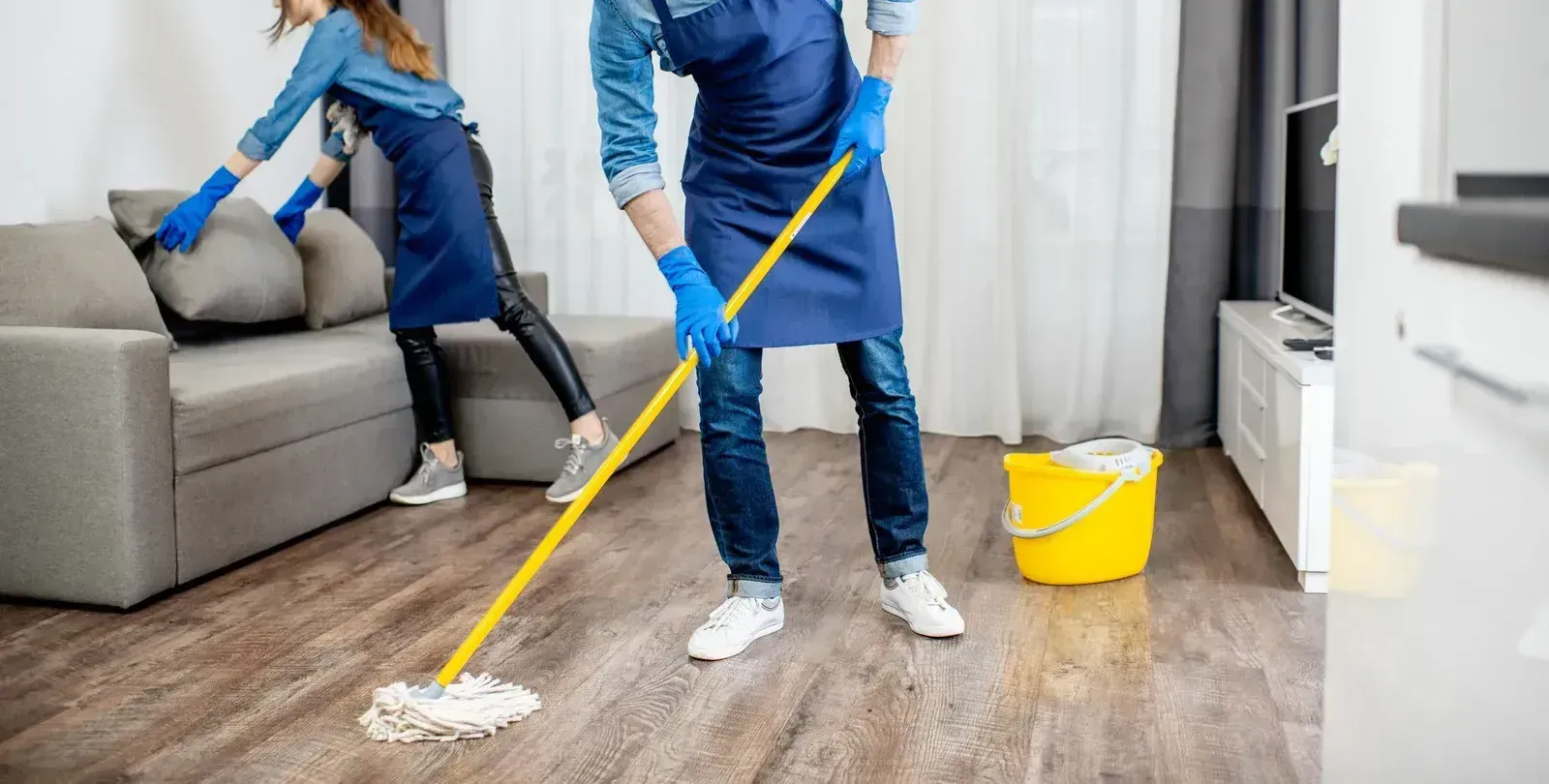 A man and a woman are cleaning the floor in a living room.
