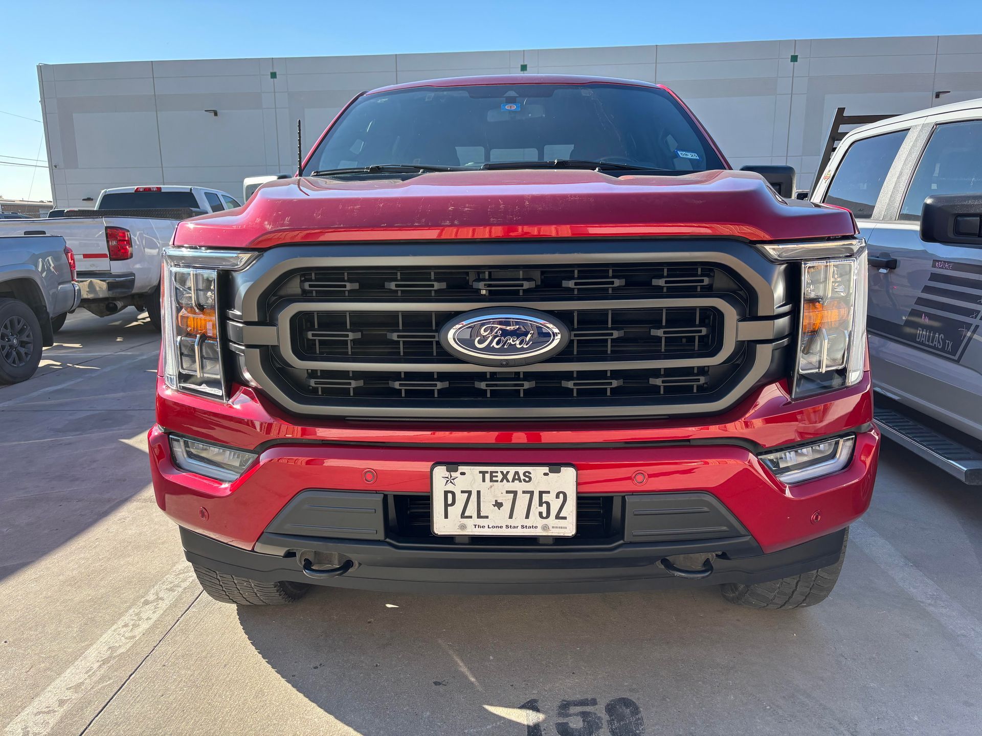 A red ford f150 truck is parked in a parking lot.