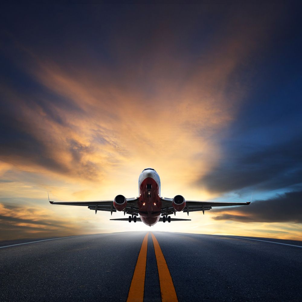 A passenger airplane taking off from a runway against a vibrant sunset sky.