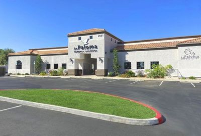 La Paloma Animal Hospital building with a front parking lot and a grass island under a clear blue sky.