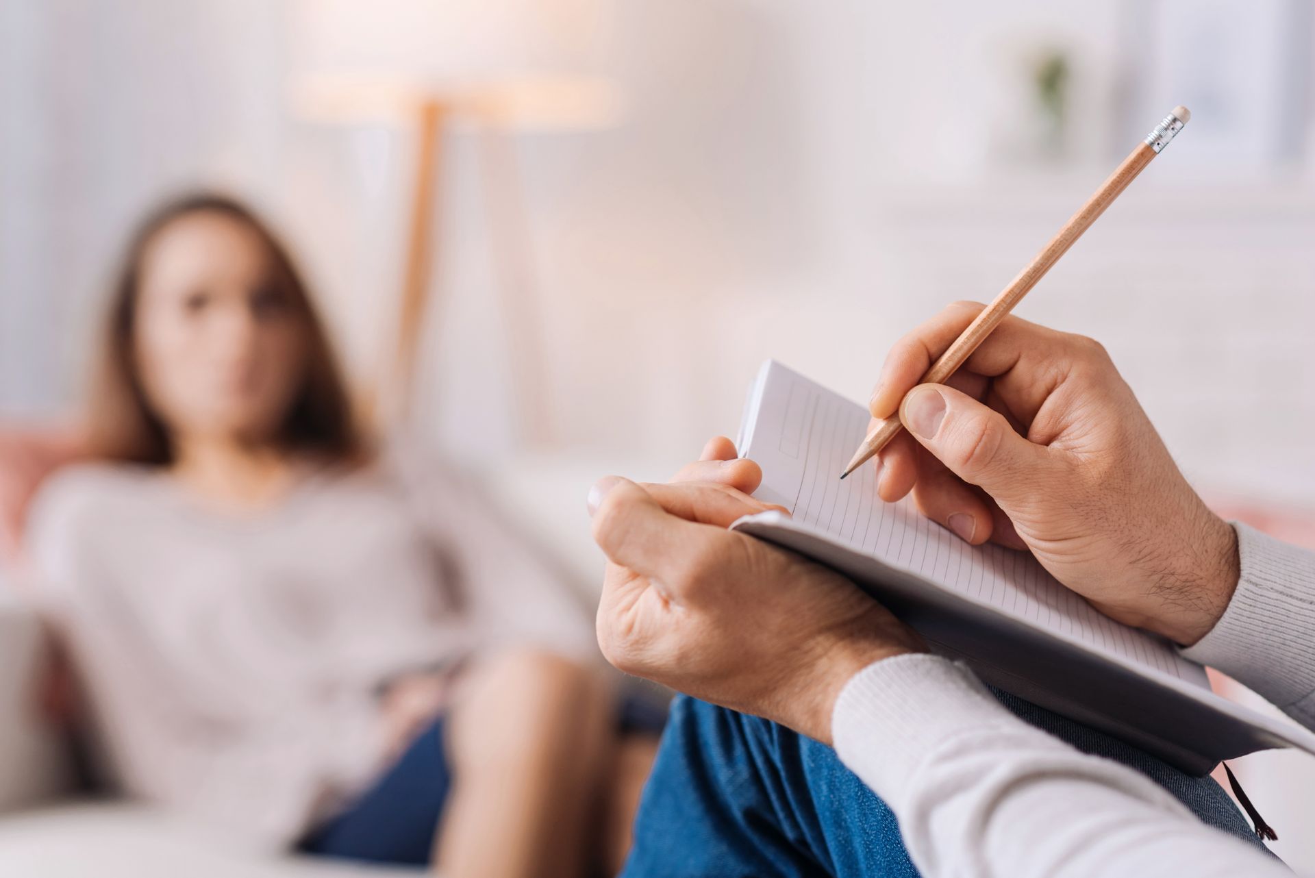 Therapist taking notes while speaking with a patient in a softly lit office