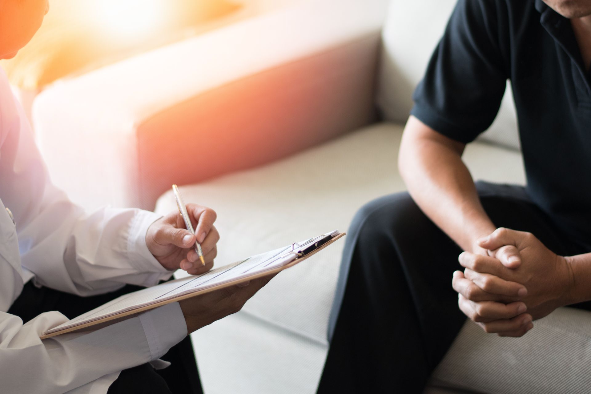 Therapist taking notes while seated with a client in a counseling session