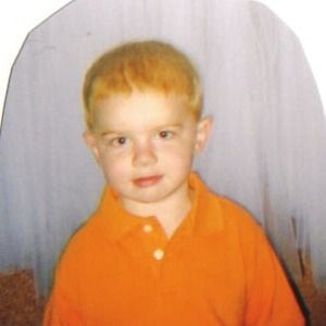 a young boy in an orange shirt is sitting in a chair