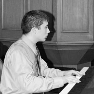 a man is playing a piano in a black and white photo .