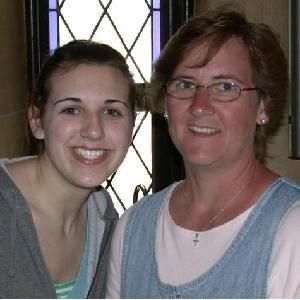 two women are posing for a picture together and smiling for the camera .