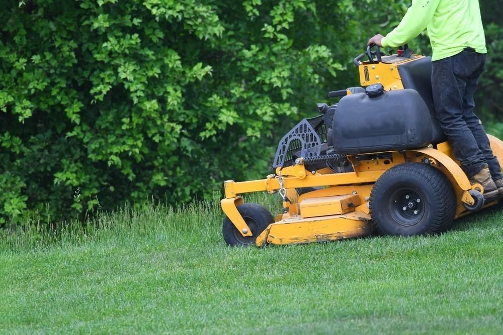 a man is riding a yellow lawn mower on a lush green lawn .